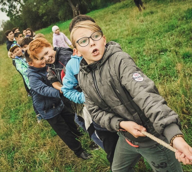 Wandertag für Schuklassen in NRW mit Zonovo Eine Schulklasse macht Tauziehen, Kinder lachen und arbeiten als Team